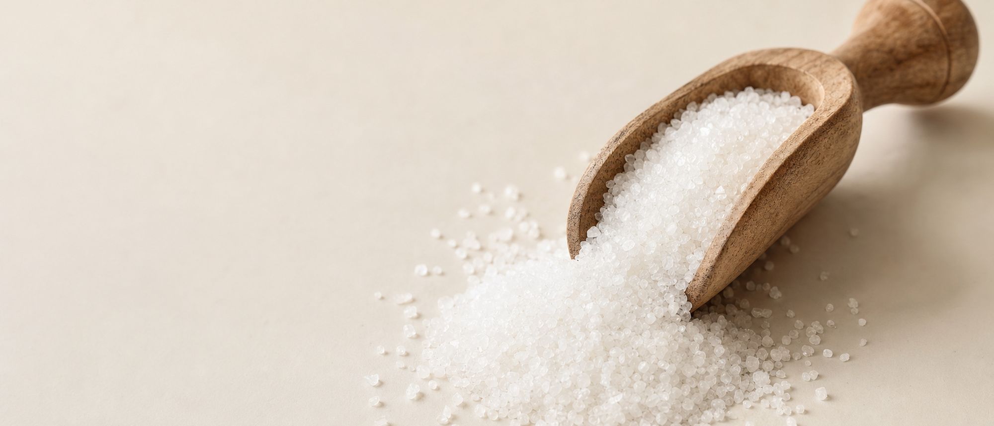 White crystal sugar in a wooden scoop